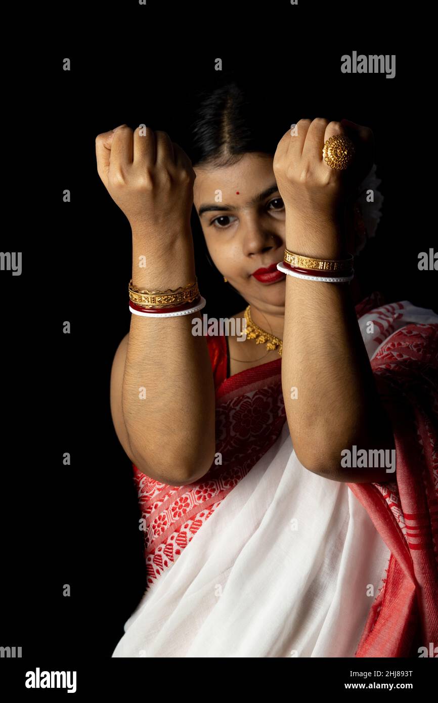 An Indian woman in red saree wearing bangles with smiling face on black background Stock Photo