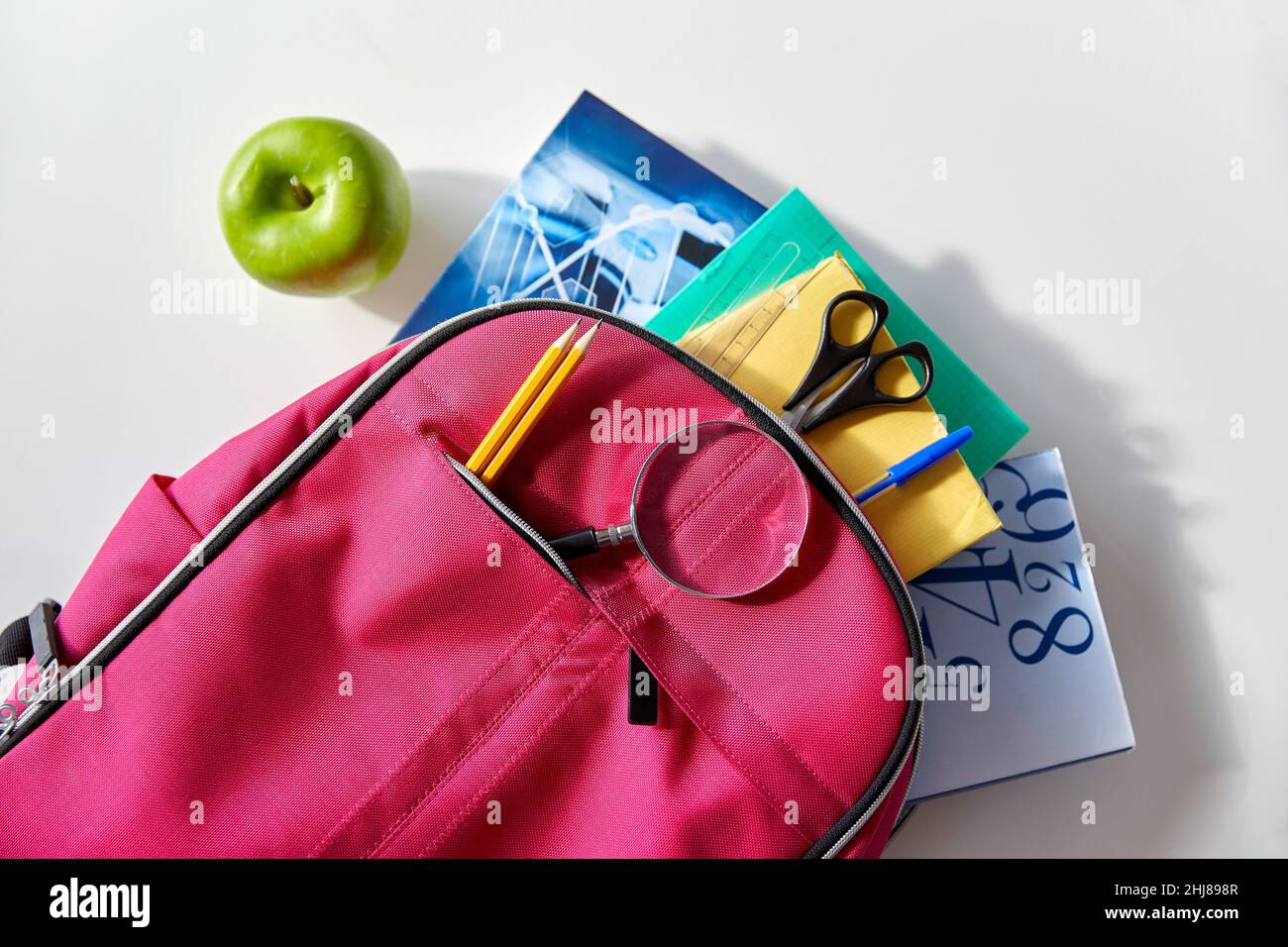 backpack with books, school supplies and apple Stock Photo