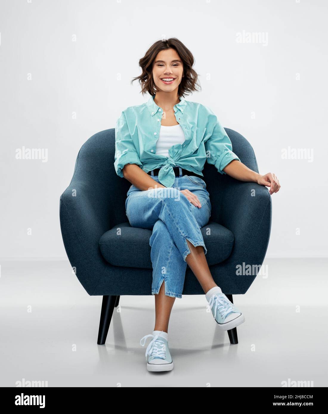 happy smiling young woman sitting in armchair Stock Photo - Alamy