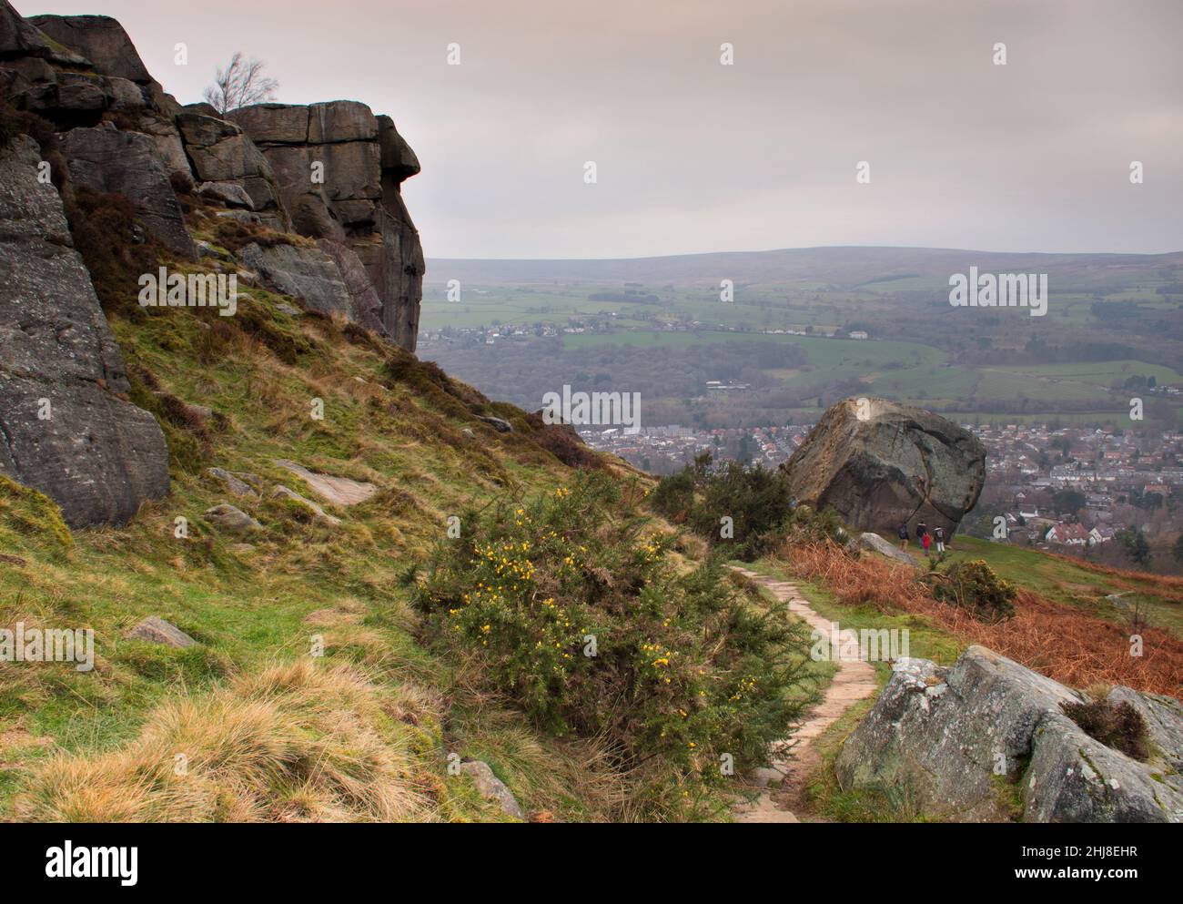 A small group of people around the 'calf' - the smaller of the two rocks in the famous Cow and Calf rock formation, Ilkley, Yorkshire, UK Stock Photo