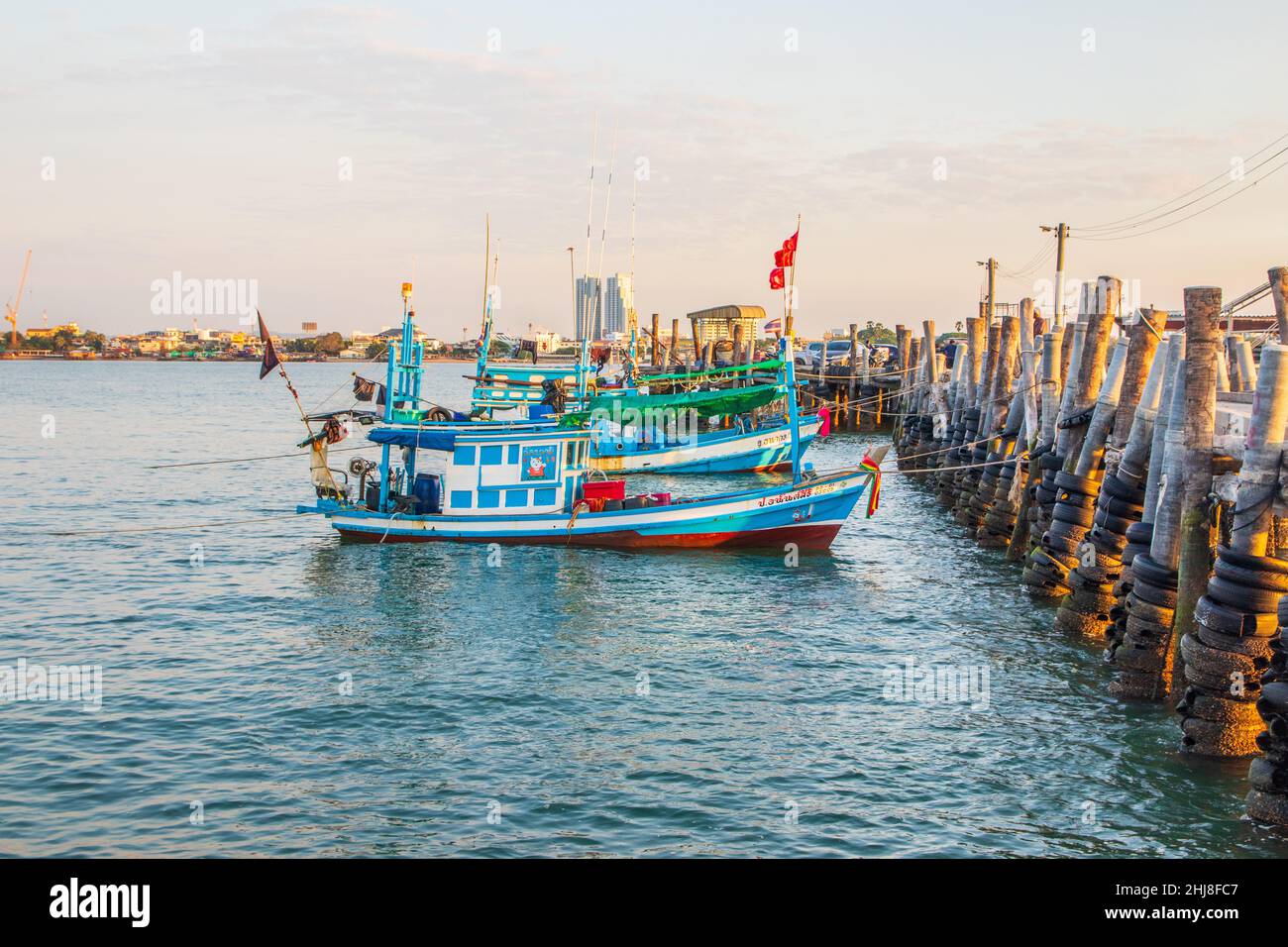 In the evening, colorful fishing boats are securely tied down directly at the pier with seaman's ropes and knots Stock Photo