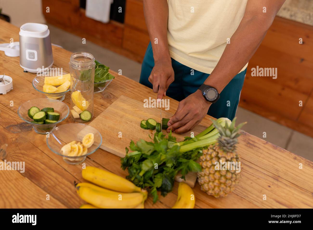 Midsection of african american young man cutting vegetables and fruits