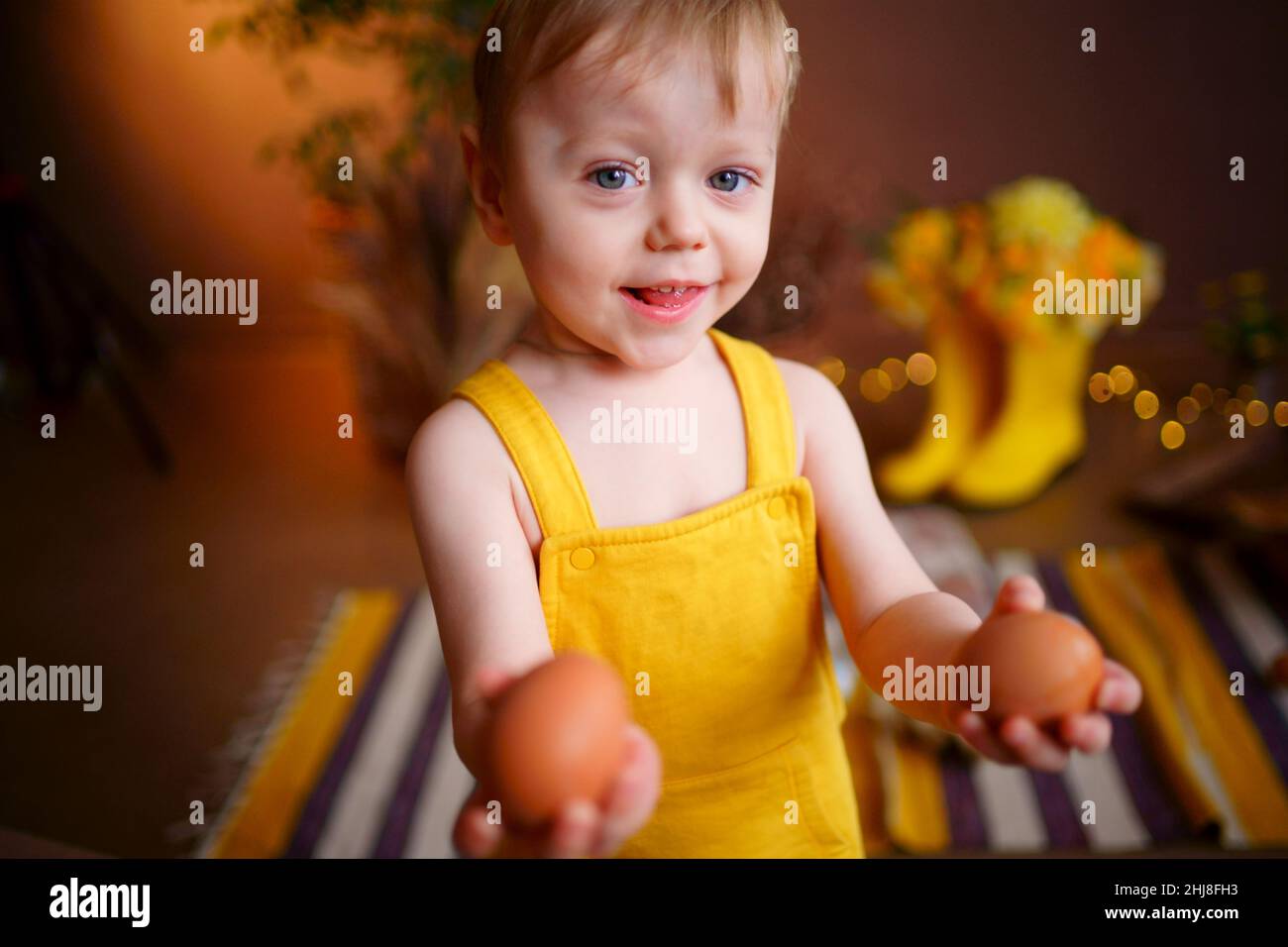 baby with easter eggs in yellow jumpsuit Stock Photo Alamy