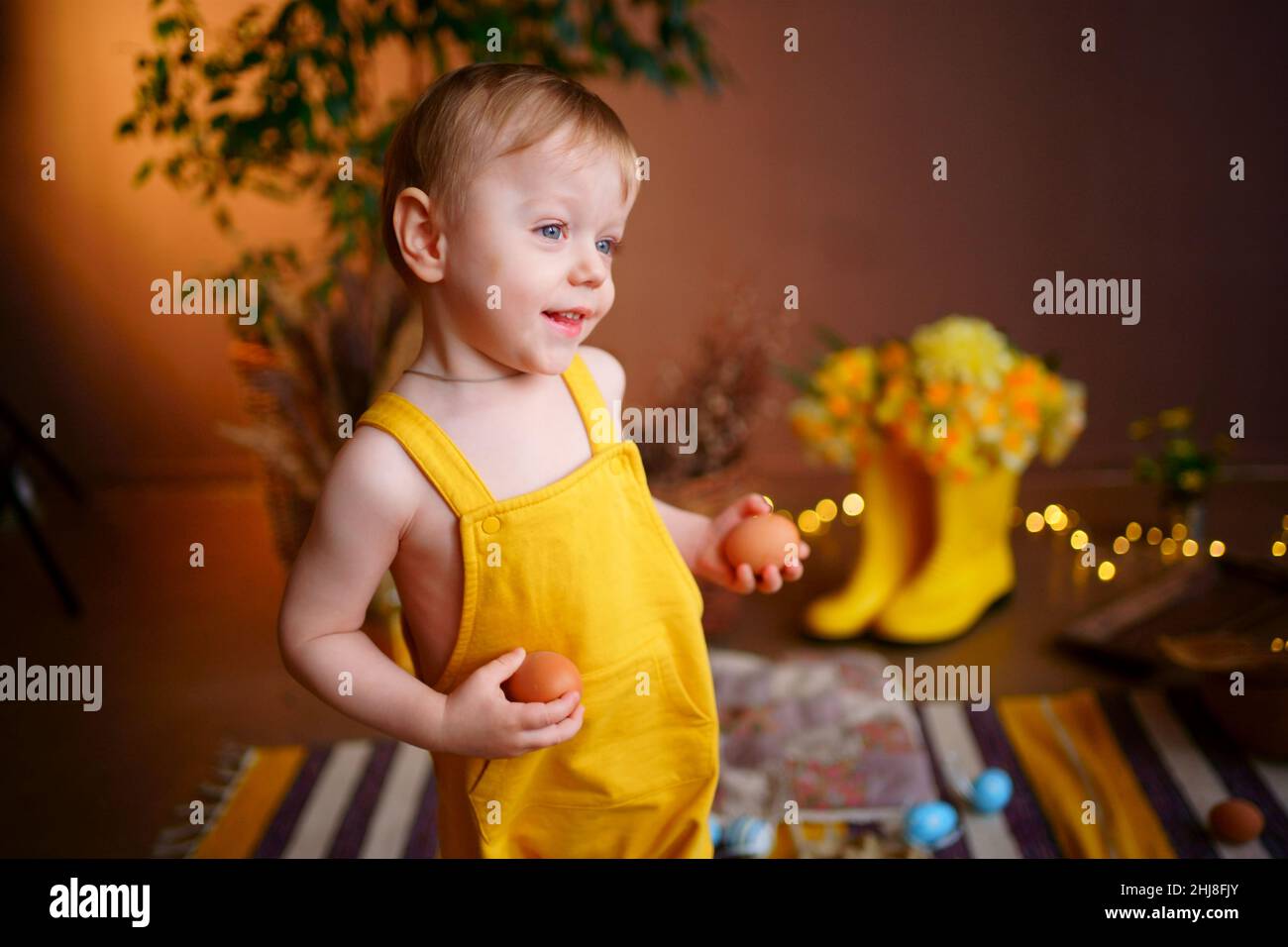 baby with easter eggs in yellow jumpsuit Stock Photo Alamy