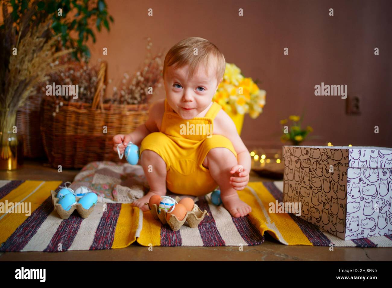 baby with easter eggs in yellow jumpsuit Stock Photo Alamy