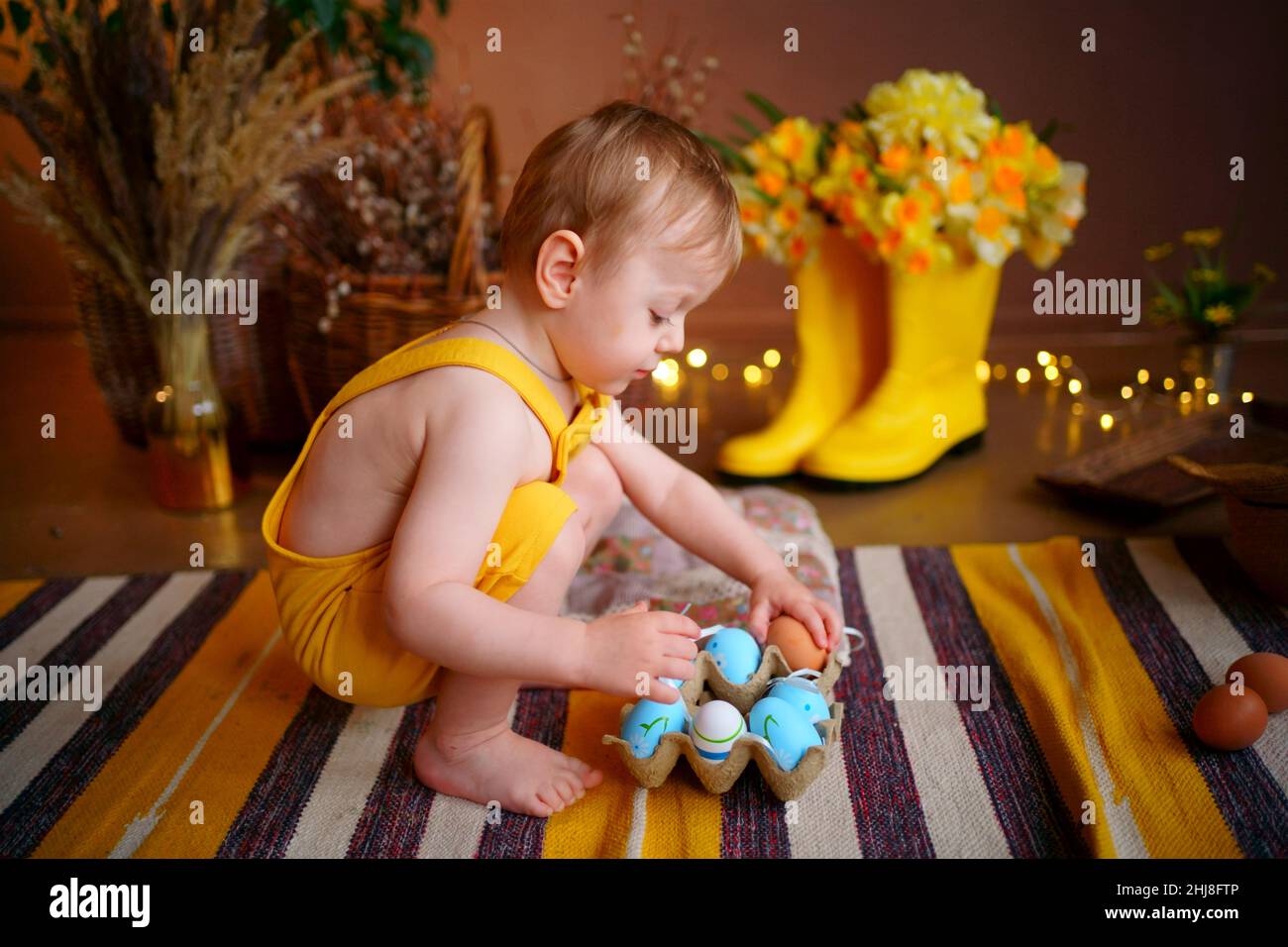 baby with easter eggs in yellow jumpsuit Stock Photo Alamy