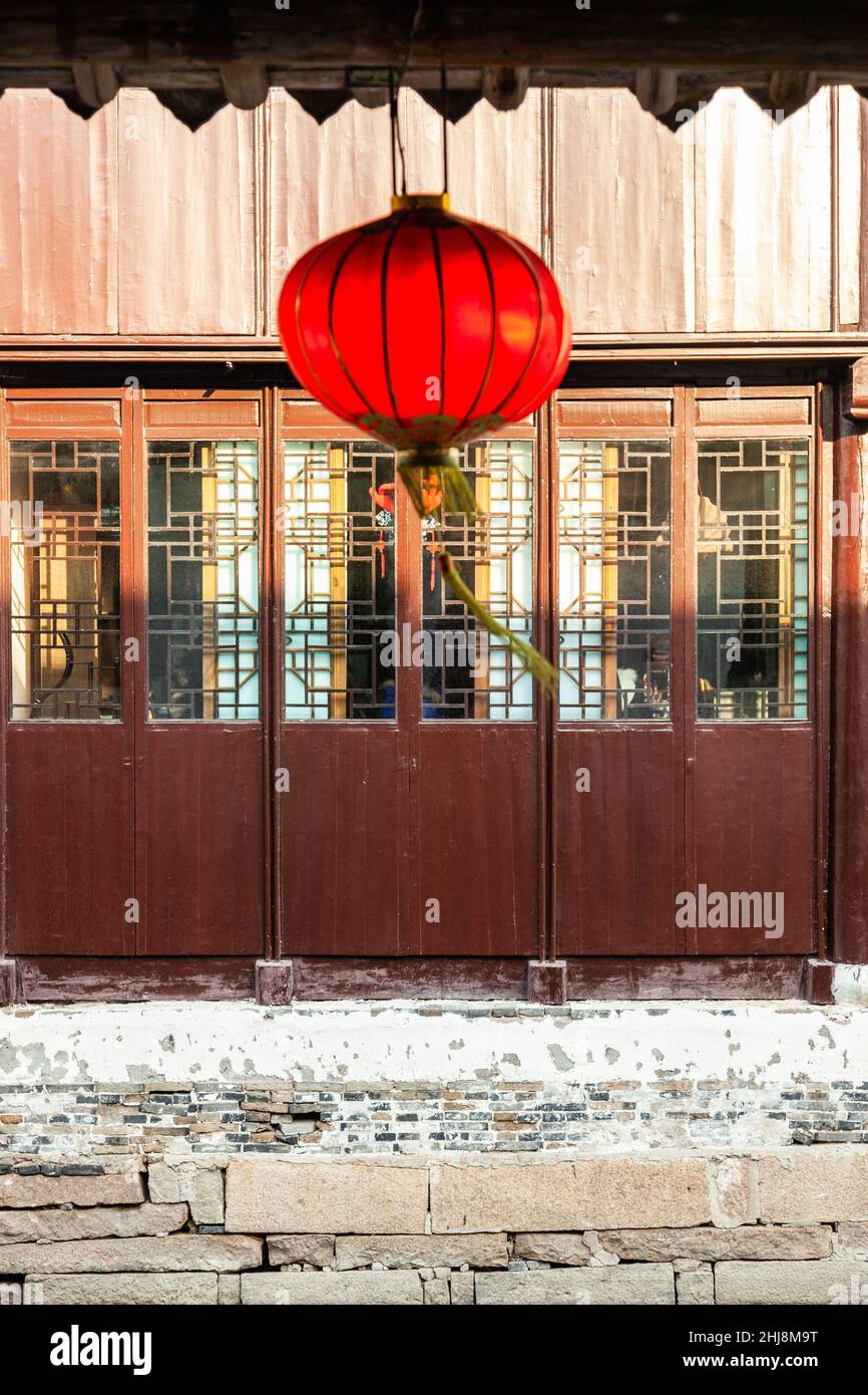 Chinese lantern hanging in front of a backlit window. View of the