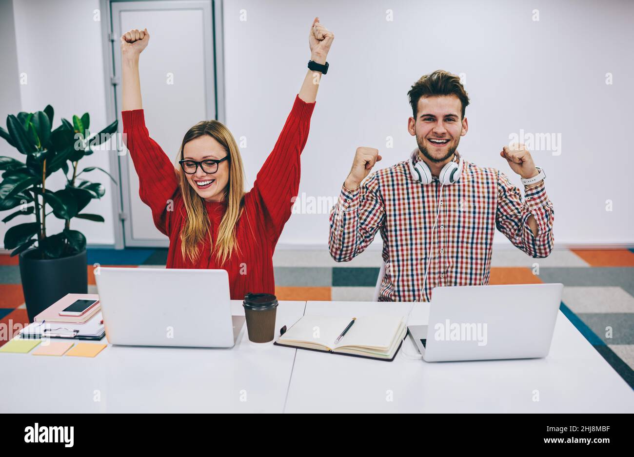 Positive colleagues celebrating success while working on laptops Stock Photo