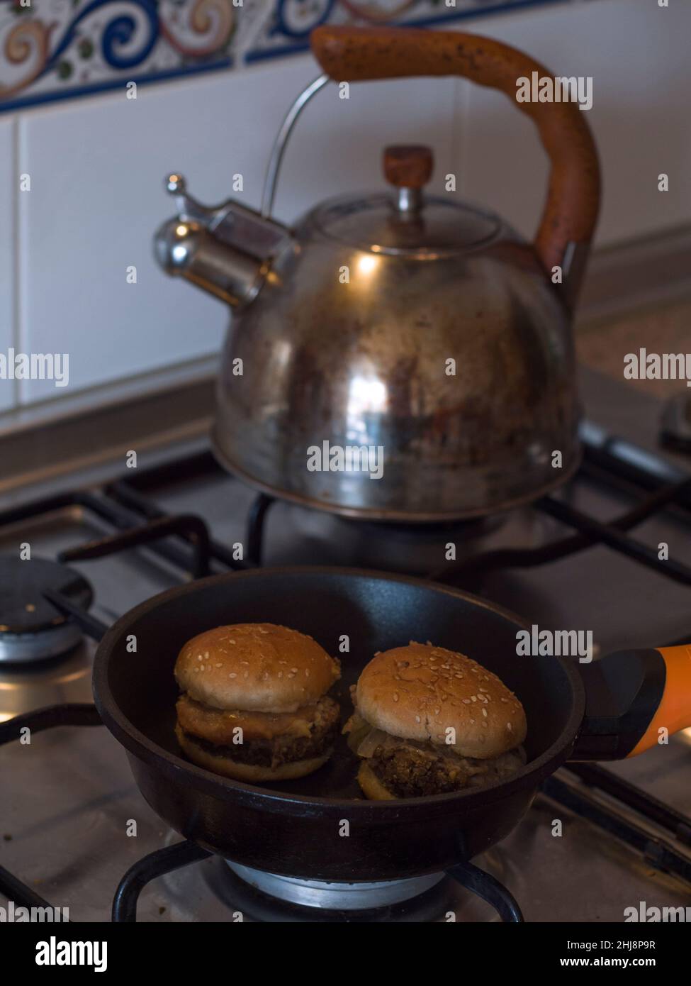 Mini veggie hamburgers being heated up in a frying pan and kettle in