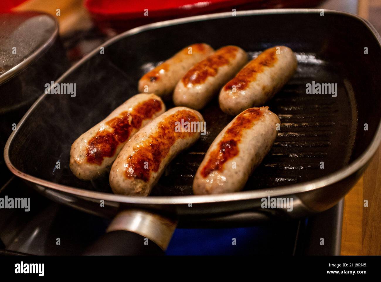 Cooking sausages in a hot grill pan Stock Photo Alamy