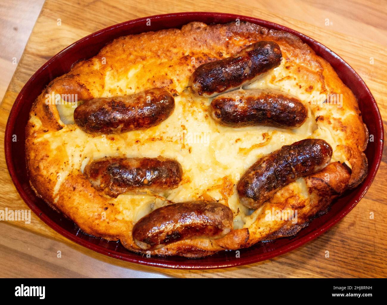 Cooking home made Toad in the Hole or sausages in batter Stock Photo