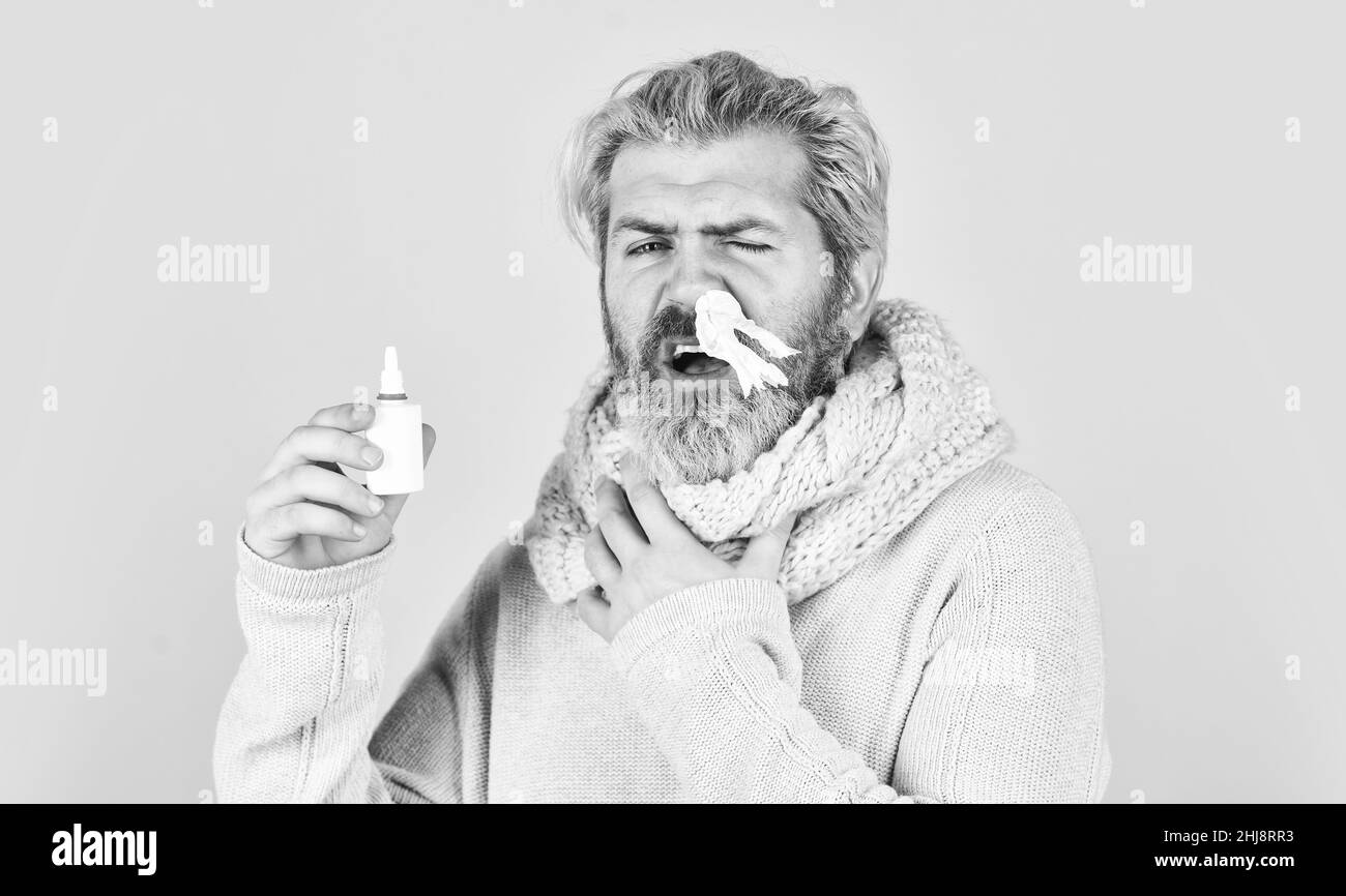 man in scarf hold nasal spray and tissue. Cold flu remedies. Runny nose