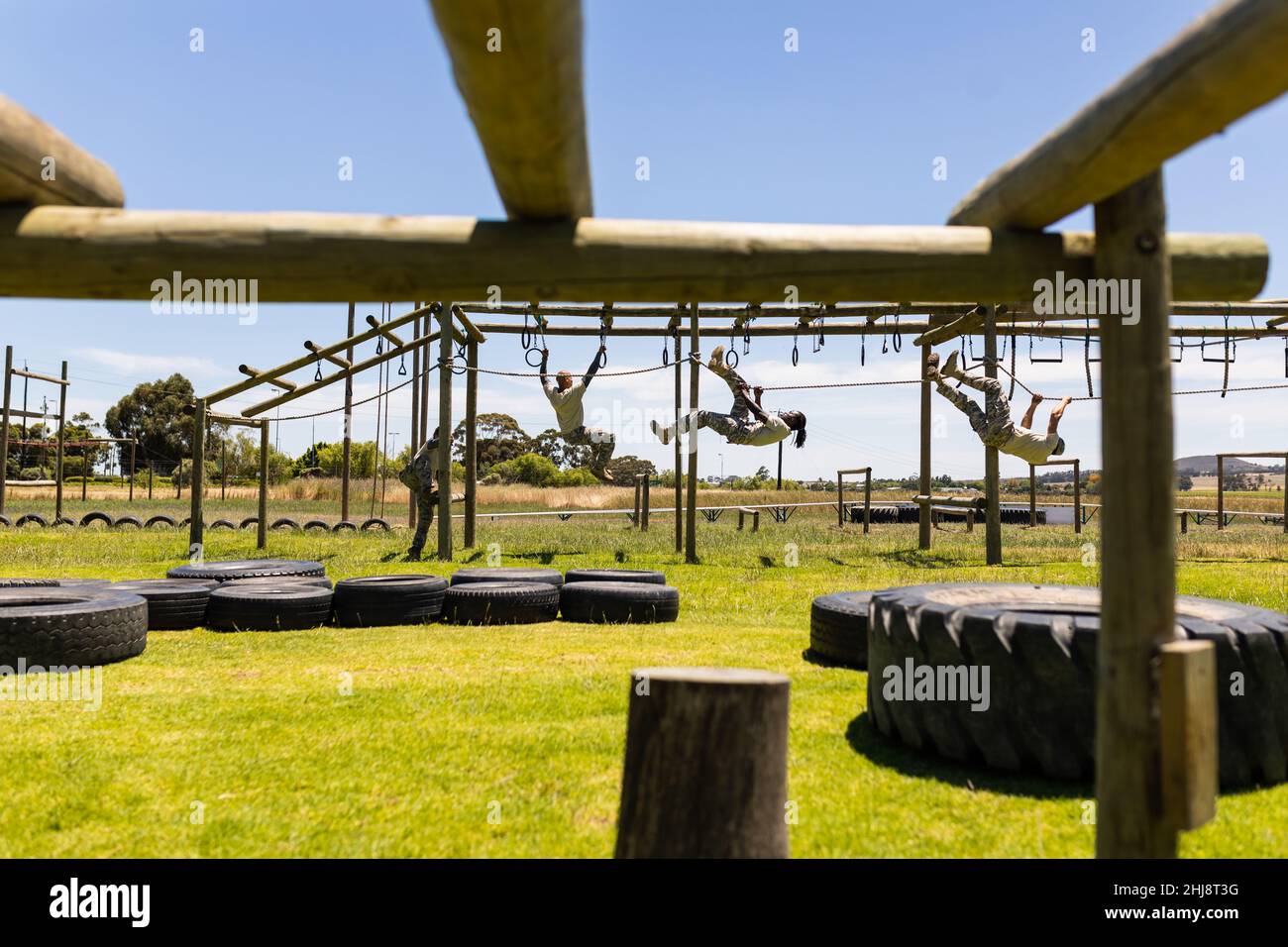 Group of male and female diverse soldiers rope climbing during obstacle course at boot camp Stock Photo