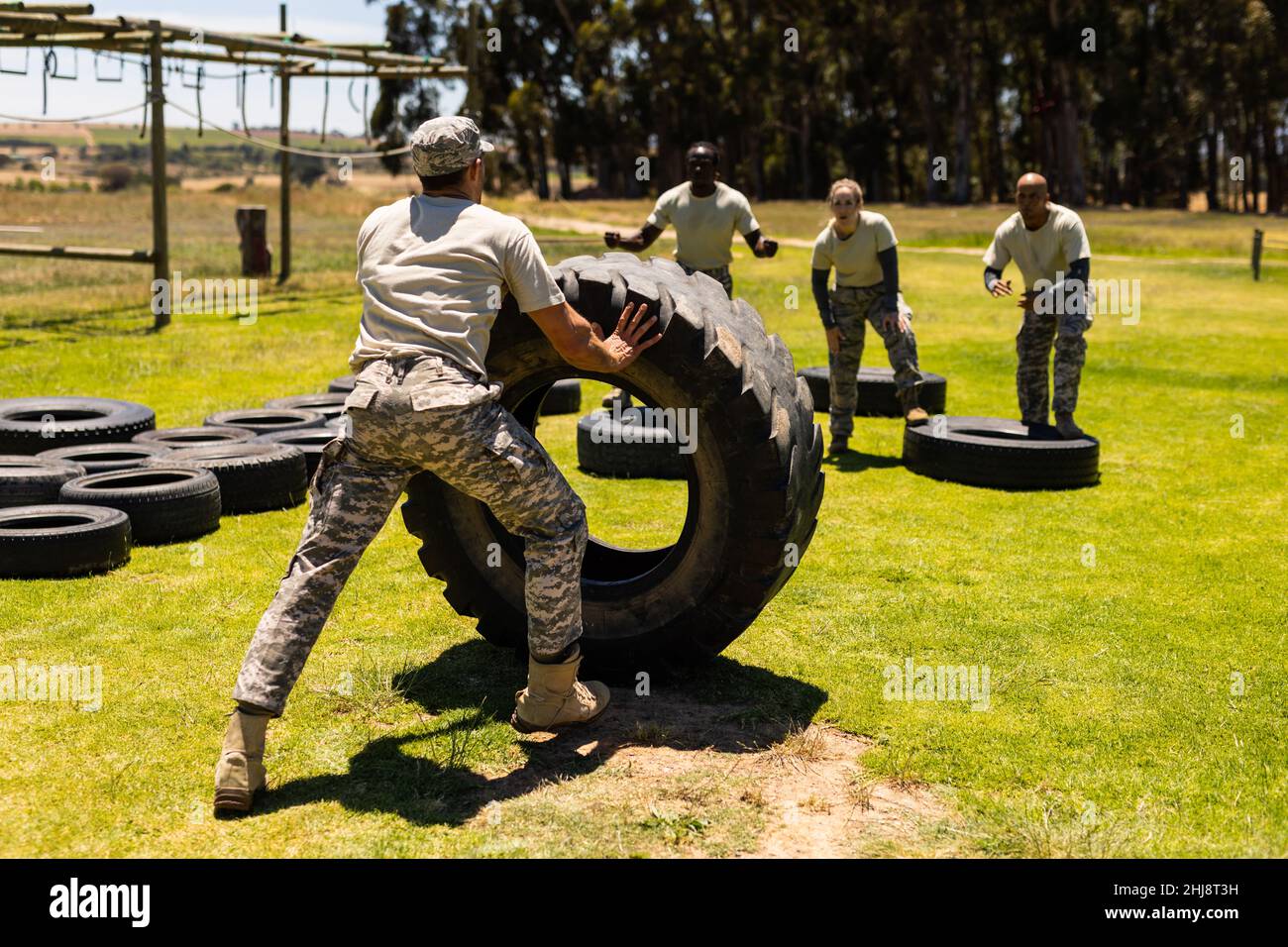 Rear view of a male soldier flipping a tire during obstacle course at boot camp Stock Photo