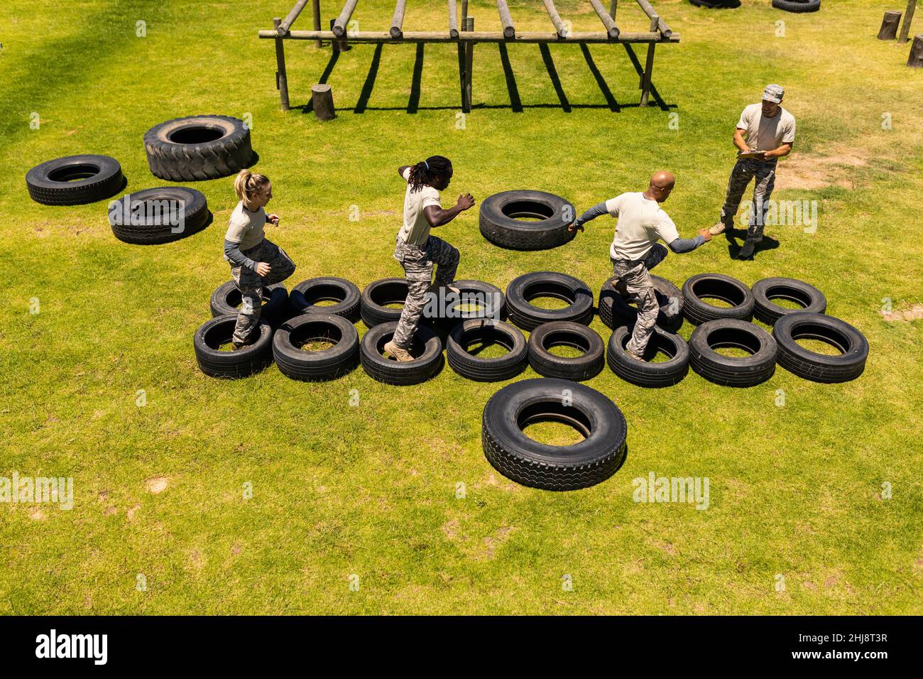 Group of male and female diverse soldiers walking on tires during obstacle course at boot camp Stock Photo