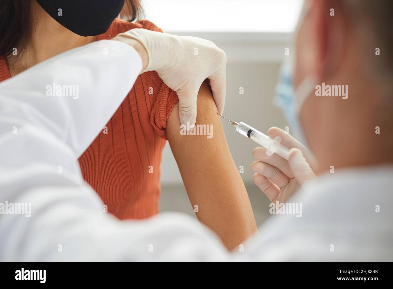 Doctor holding syringe and giving flu or Covid-19 vaccine injection to his patient Stock Photo