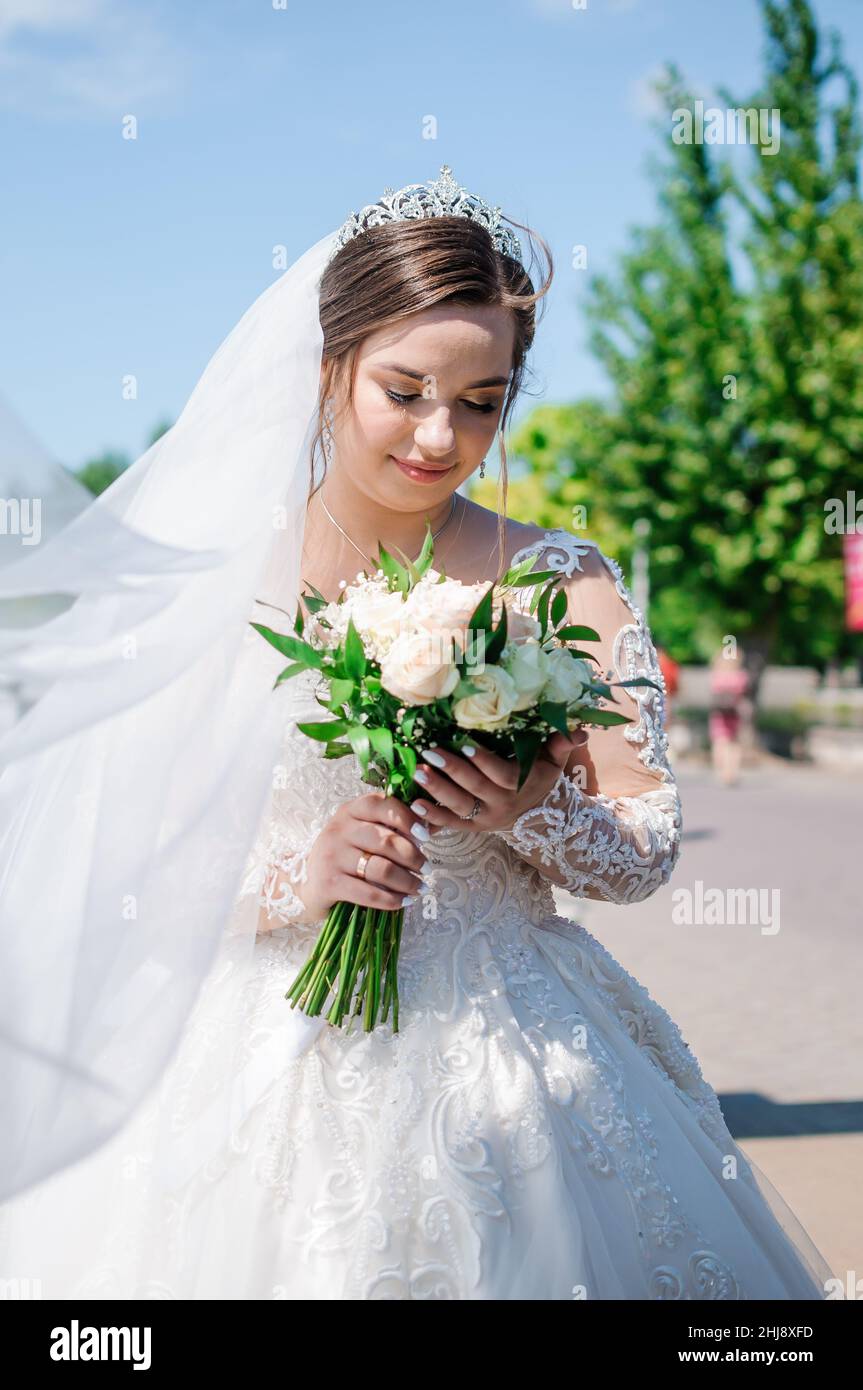 Portrait of a bride in a beautiful white dress on a green background ...