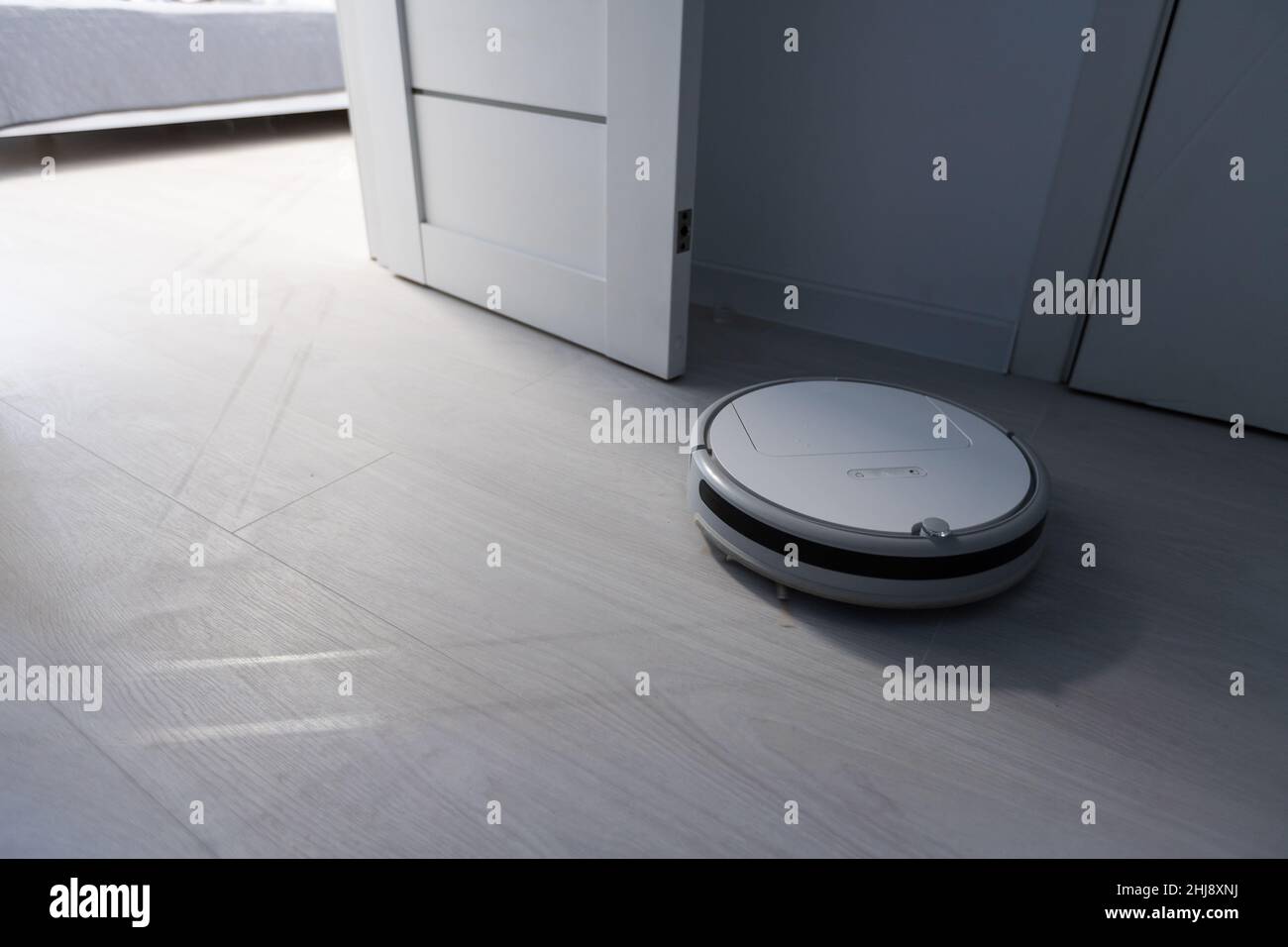 Wireless Robotic vacuum cleaner cleaning a wooden floor in living room ...