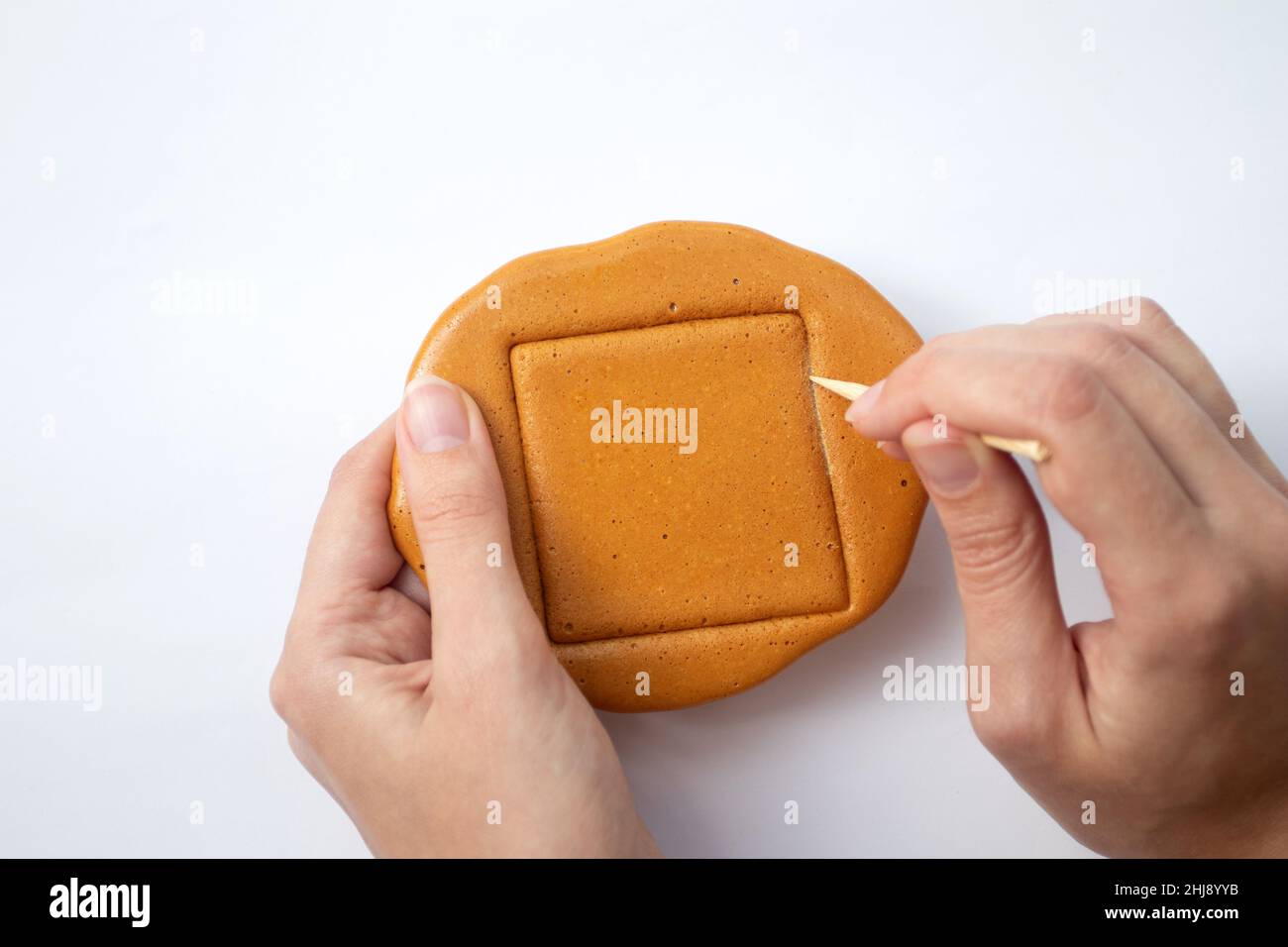 Hands playing with Dalgona candy. South Korea honeycomb Stock Photo