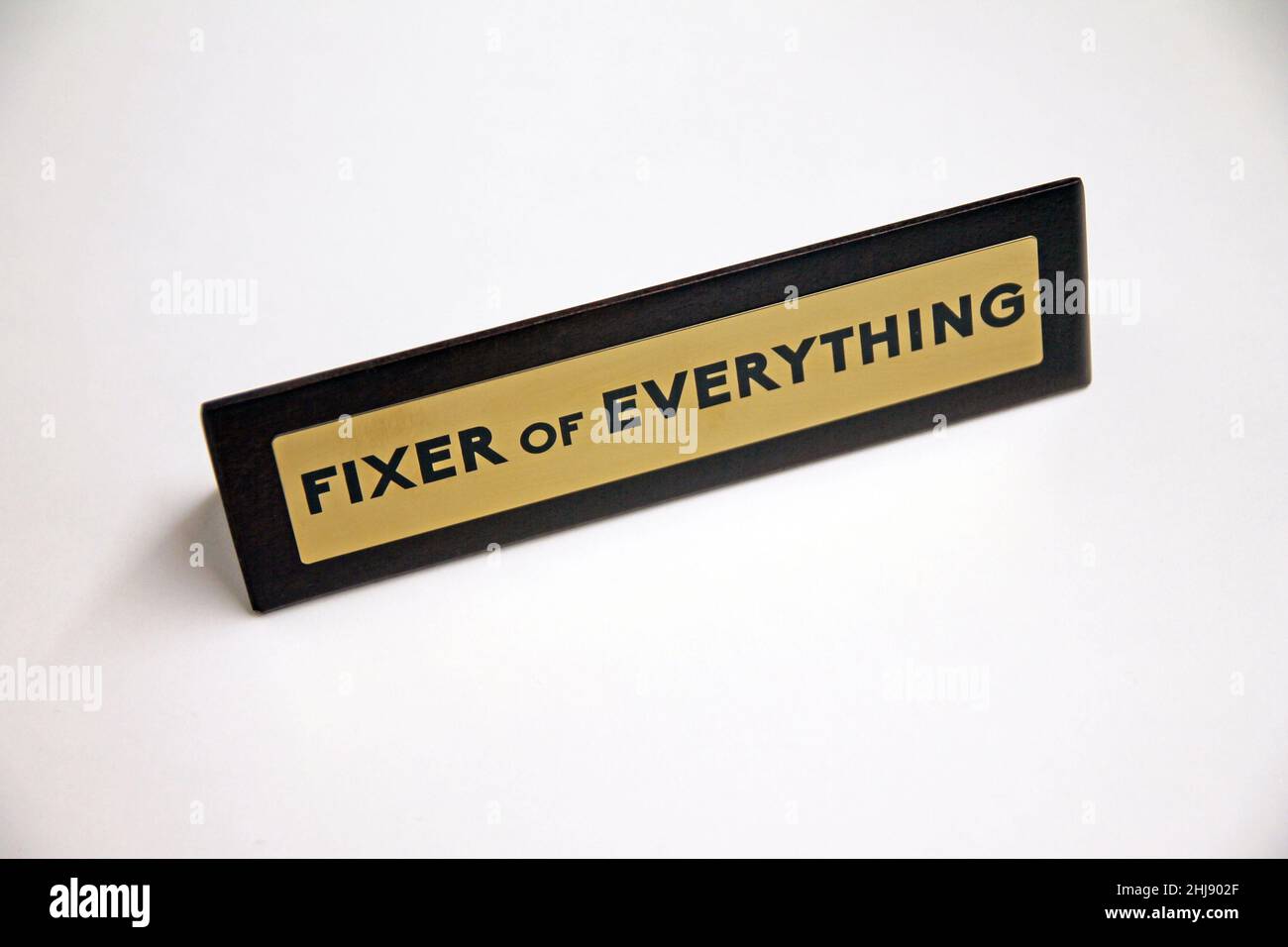 Fixer of Everything wood and metal sign on a white shelf in office life Stock Photo