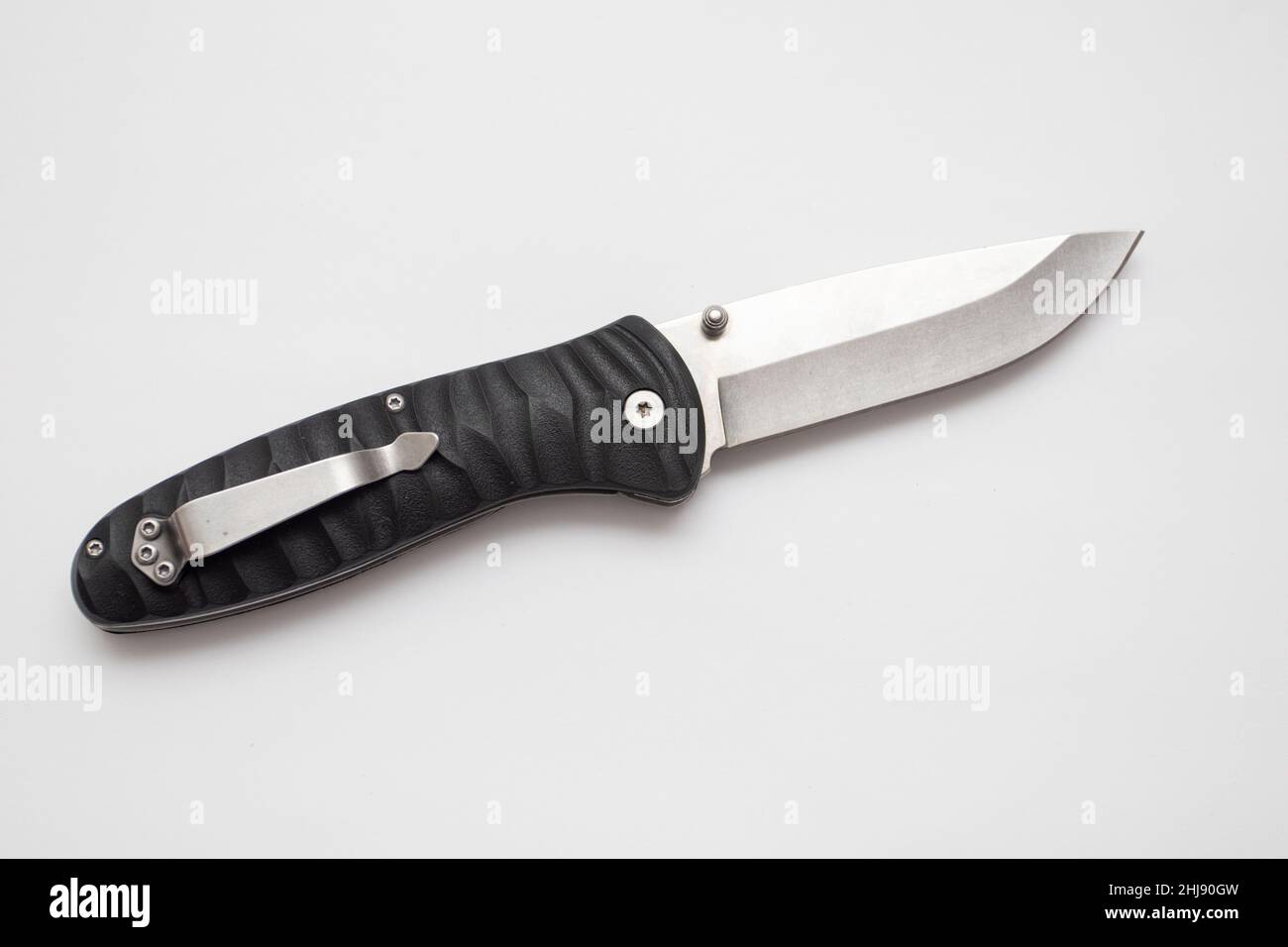 Folding hunting knife with black handle on white background. Stock Photo