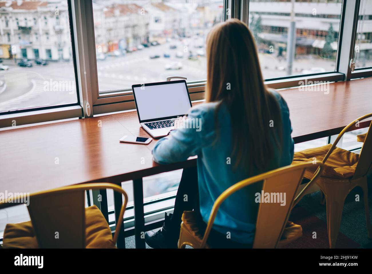 Woman using laptop at table near window Stock Photo
