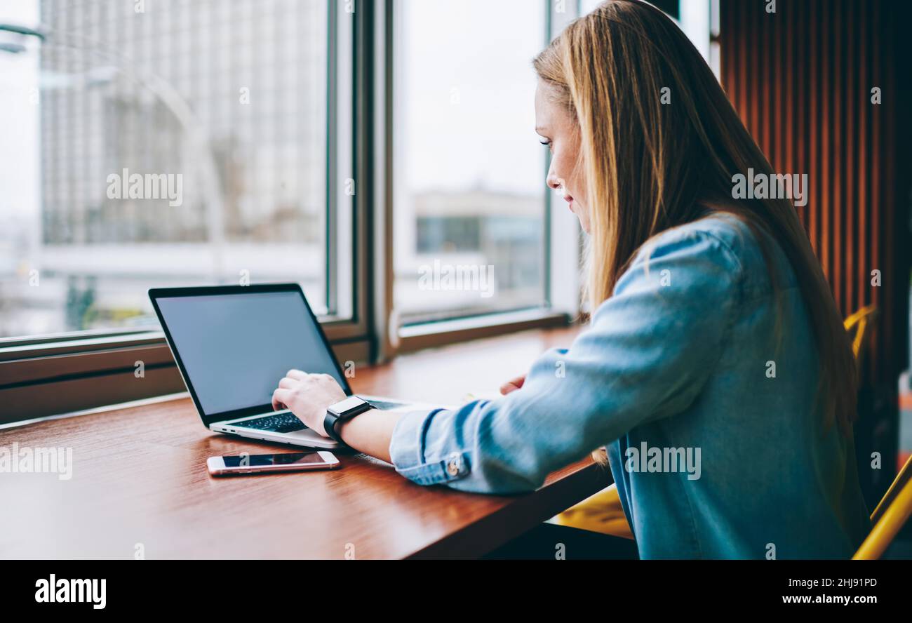 Woman browsing laptop while working near window Stock Photo - Alamy