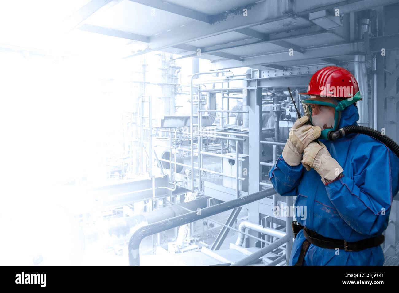 Chemical worker in full personal chemical protection, talking into a walkie-talkie. Left side of image fading out for editors purpose. Stock Photo