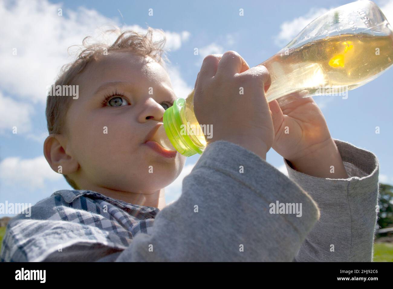 toddler drinking apple juice from baby bottle Stock Photo