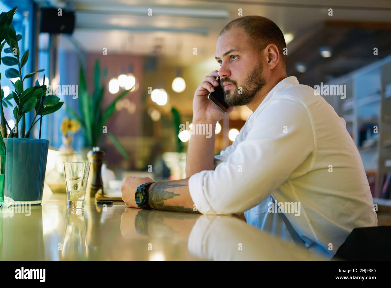 Pensive man talking on phone in cafe Stock Photo