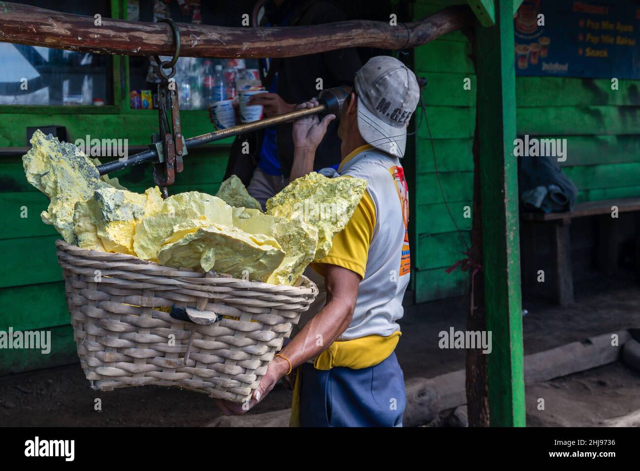 Miners of the Ijen Volcano in Indonesia weigh their baskets full of native sulfur at a steelyard balance Stock Photo