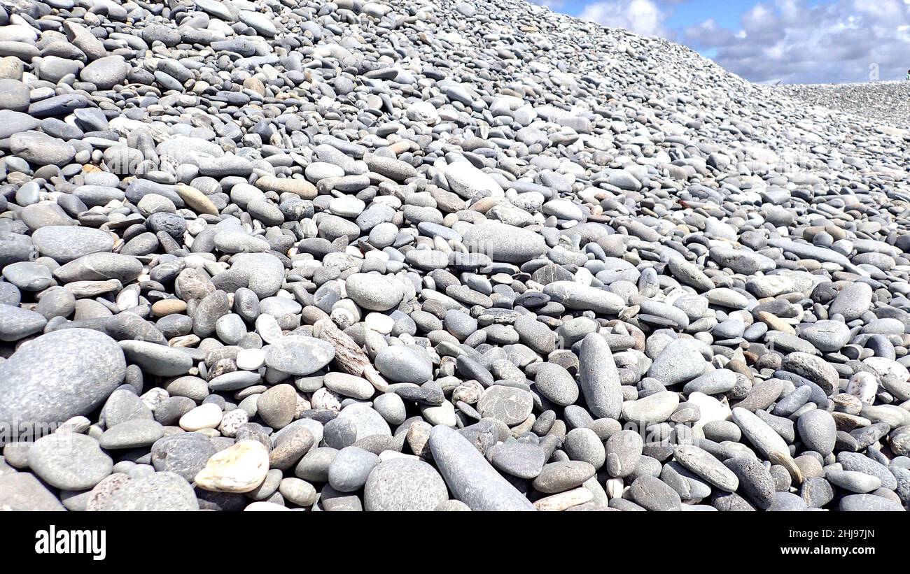 Massive banks of grey stones over sand dunes on Greymouth Beach, NZ Stock Photo