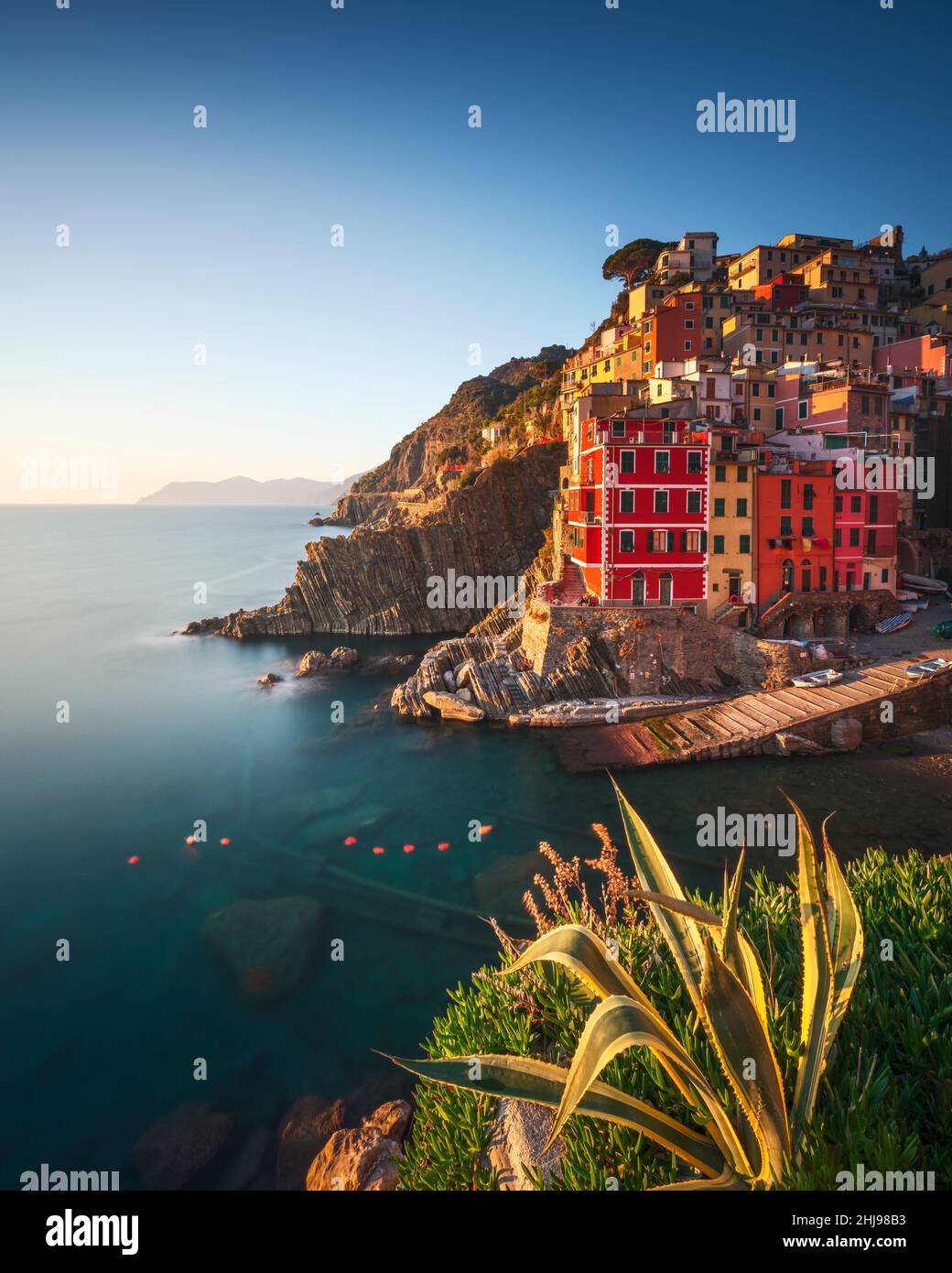Riomaggiore town, cape and sea at sunset. Seascape in Cinque Terre National Park, Liguria, Italy, Europe. Long Exposure Photography Stock Photo