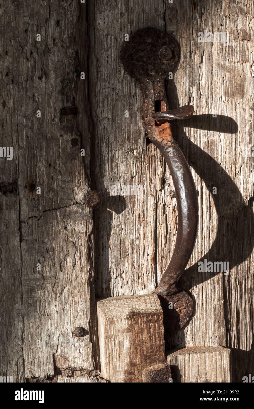 Heavy duty metal vertical thumb latch door handle on old wooden door Stock Photo