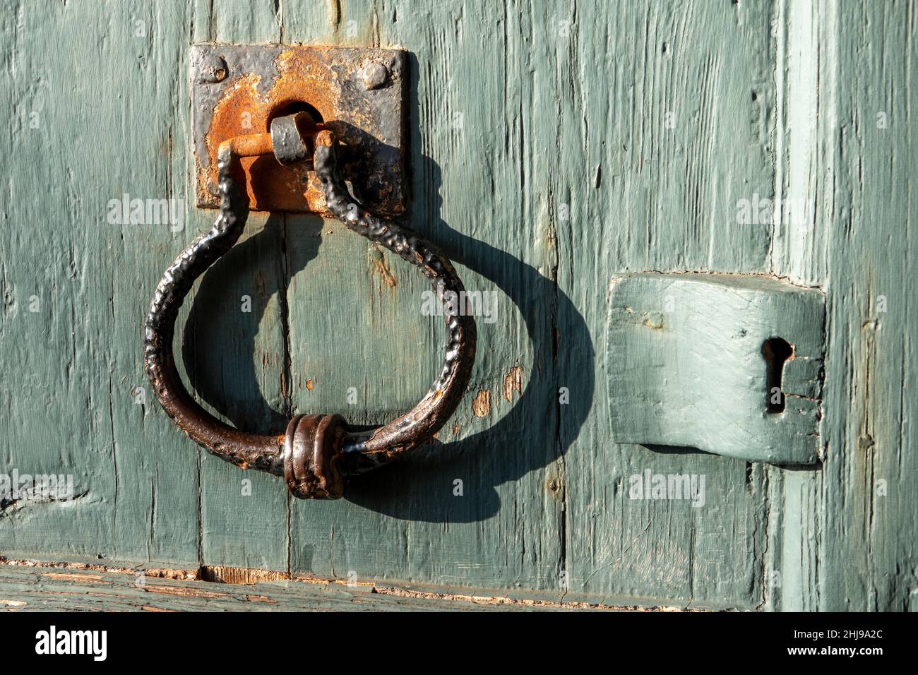 Heavy duty well worn metal door handle on old wooden painted door with