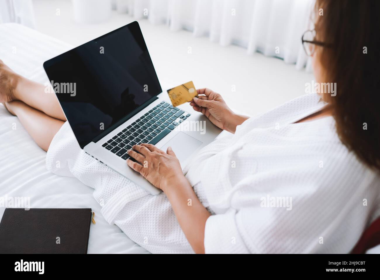 Woman lying on bed with laptop and credit card Stock Photo Alamy