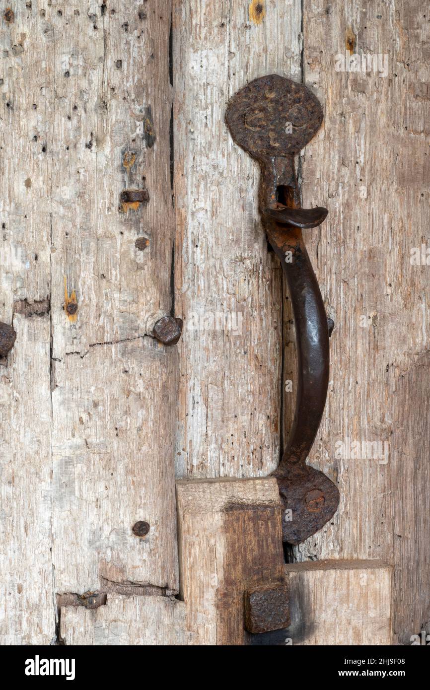 Vertical well worn ancient traditional thumb latch on wooden church door Stock Photo