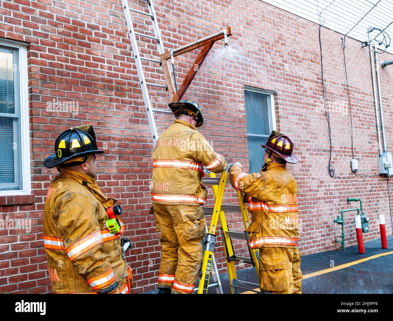 Firefighters drill on sprinkler system in turnout gear Stock Photo Alamy