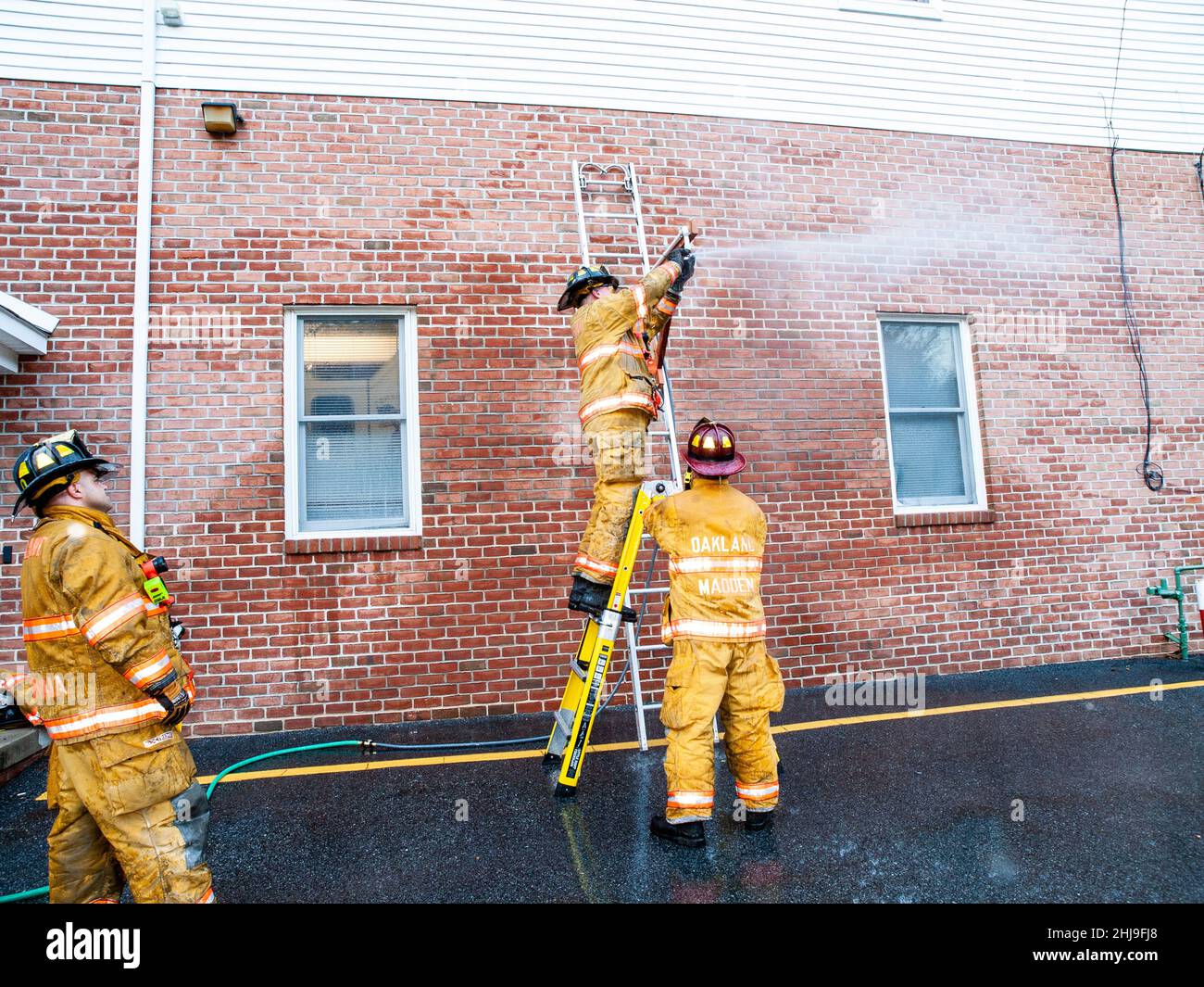Firefighters drill on sprinkler system in turnout gear Stock Photo Alamy