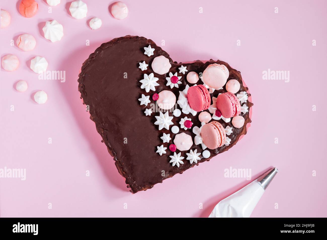 Top view of Pink heart shaped cake with chocolate glaze, meringues