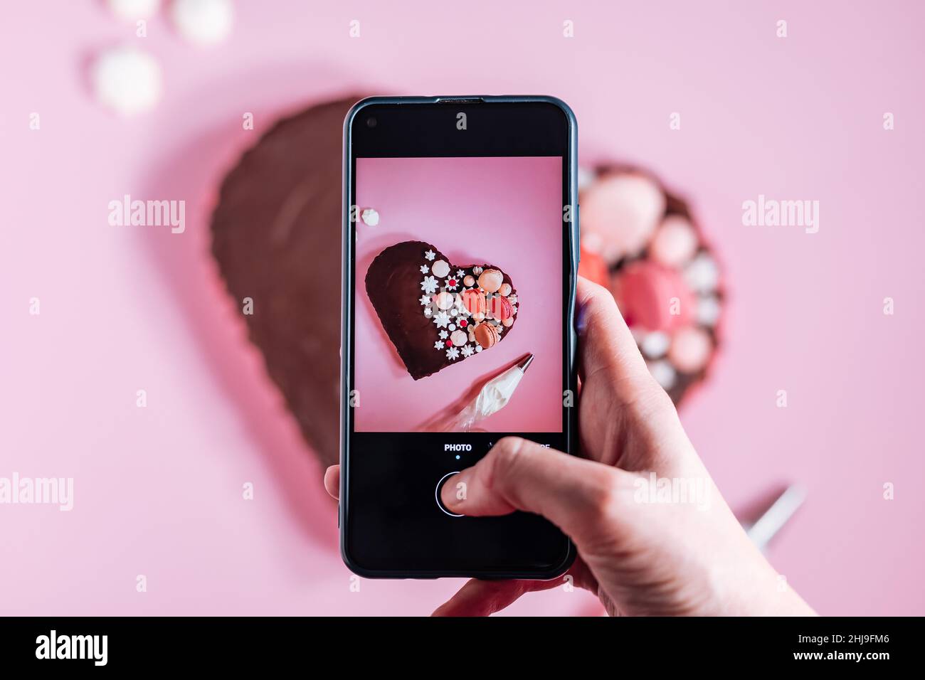 Top view of Pink heart shaped cake with chocolate glaze, meringues