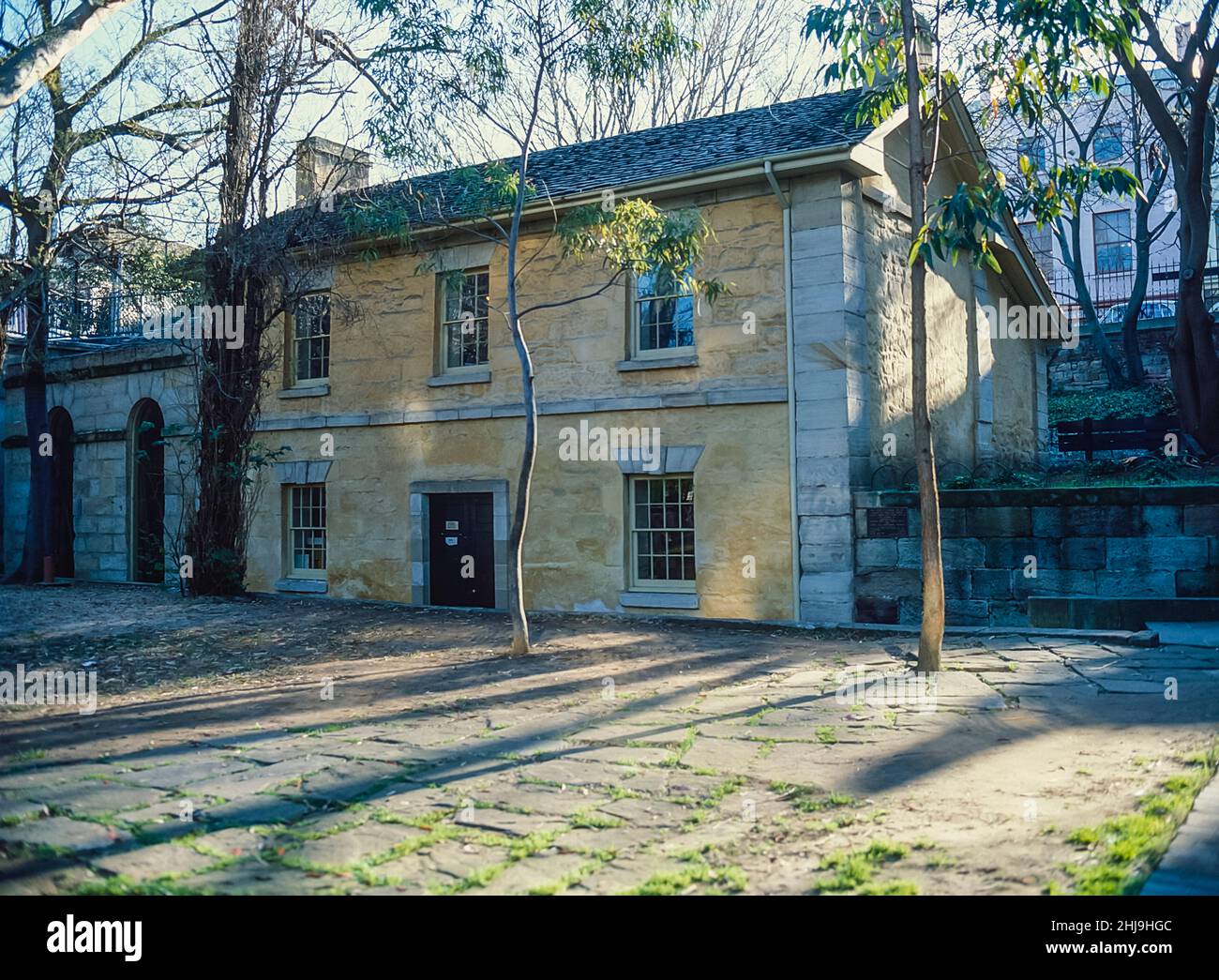 The image is of Captain Cadman's cottage-house, located at the Rocks Historical District of Sydney being an early example of Official Colonial Buildings and noted as the oldest house in Sydney dating back to 1816. The house originally being used as a waterfront police station to control government boats, their operations and crews being the residence of Government Coxswain. John Cadman was the longest serving Coxswain. originally transported to NSW as a convict, he was pardoned in 1814. He was appointed Coxswain in 1827 and served until 1845 being resident with his family at the Cottage Stock Photo