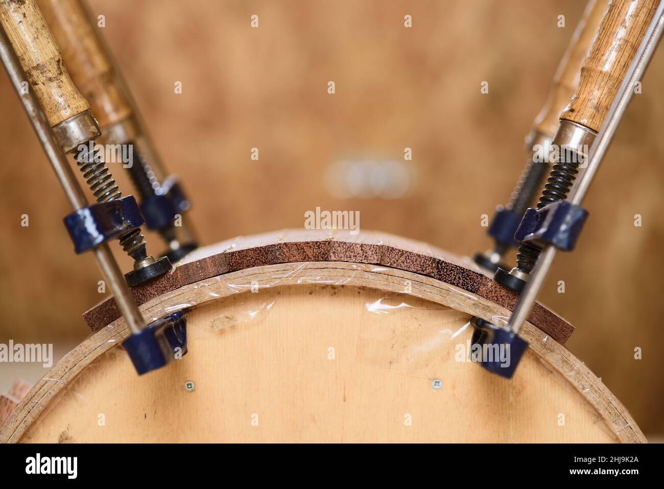 Handmade wooden drum shell held in clamp for glueing closeup Stock