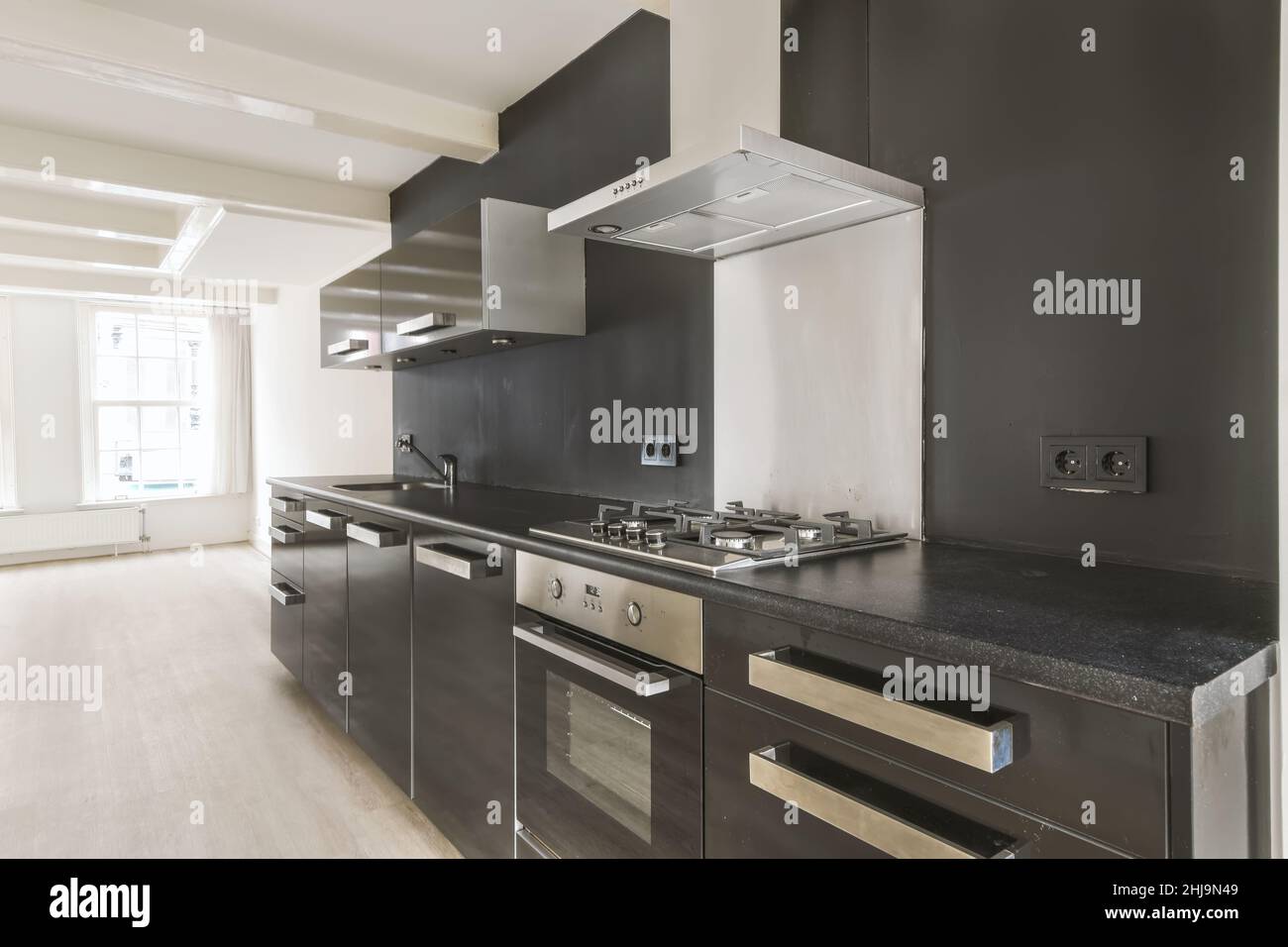 https://c8.alamy.com/comp/2HJ9N49/interior-of-a-bright-empty-room-with-modern-kitchen-appliances-with-black-cabinets-2HJ9N49.jpg