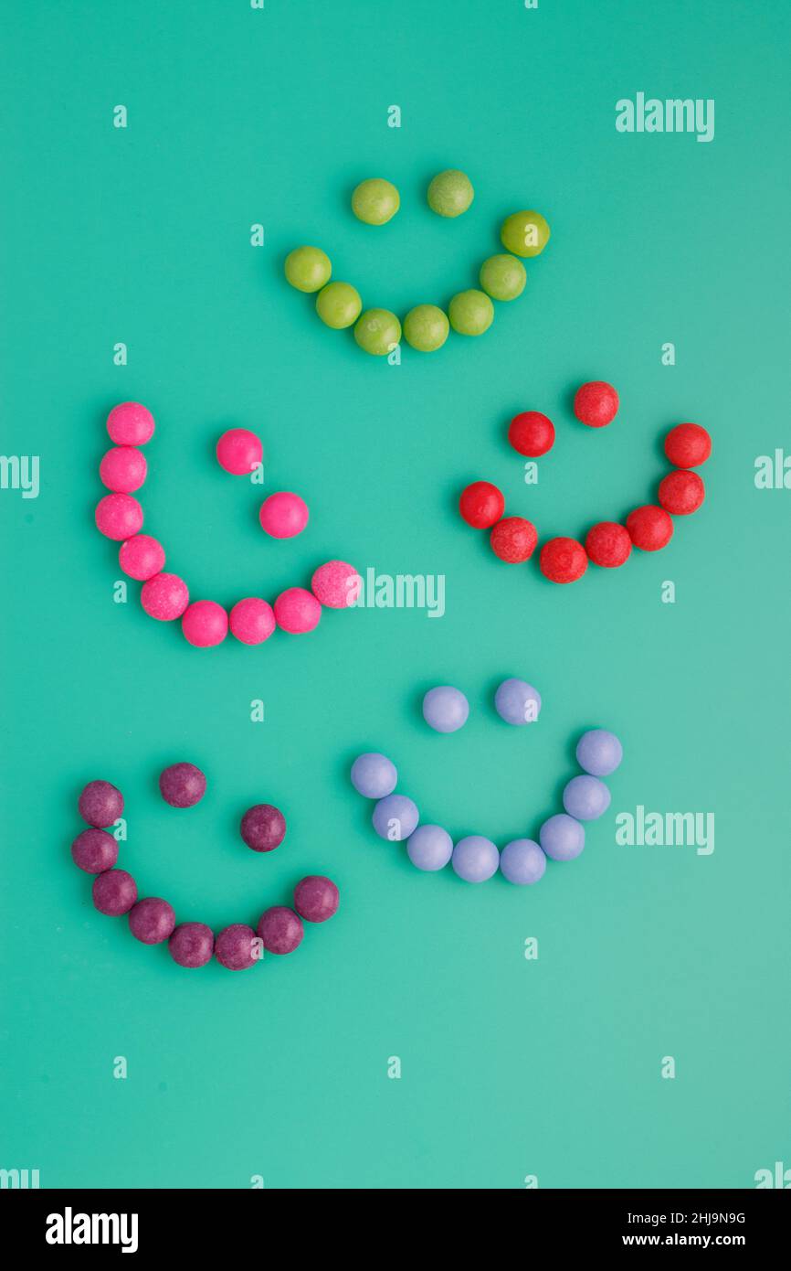 Lively, colorful candy smileys on a bright green background, which delights children and makes them smile. Charming wallpaper, place for text. Positiv Stock Photo