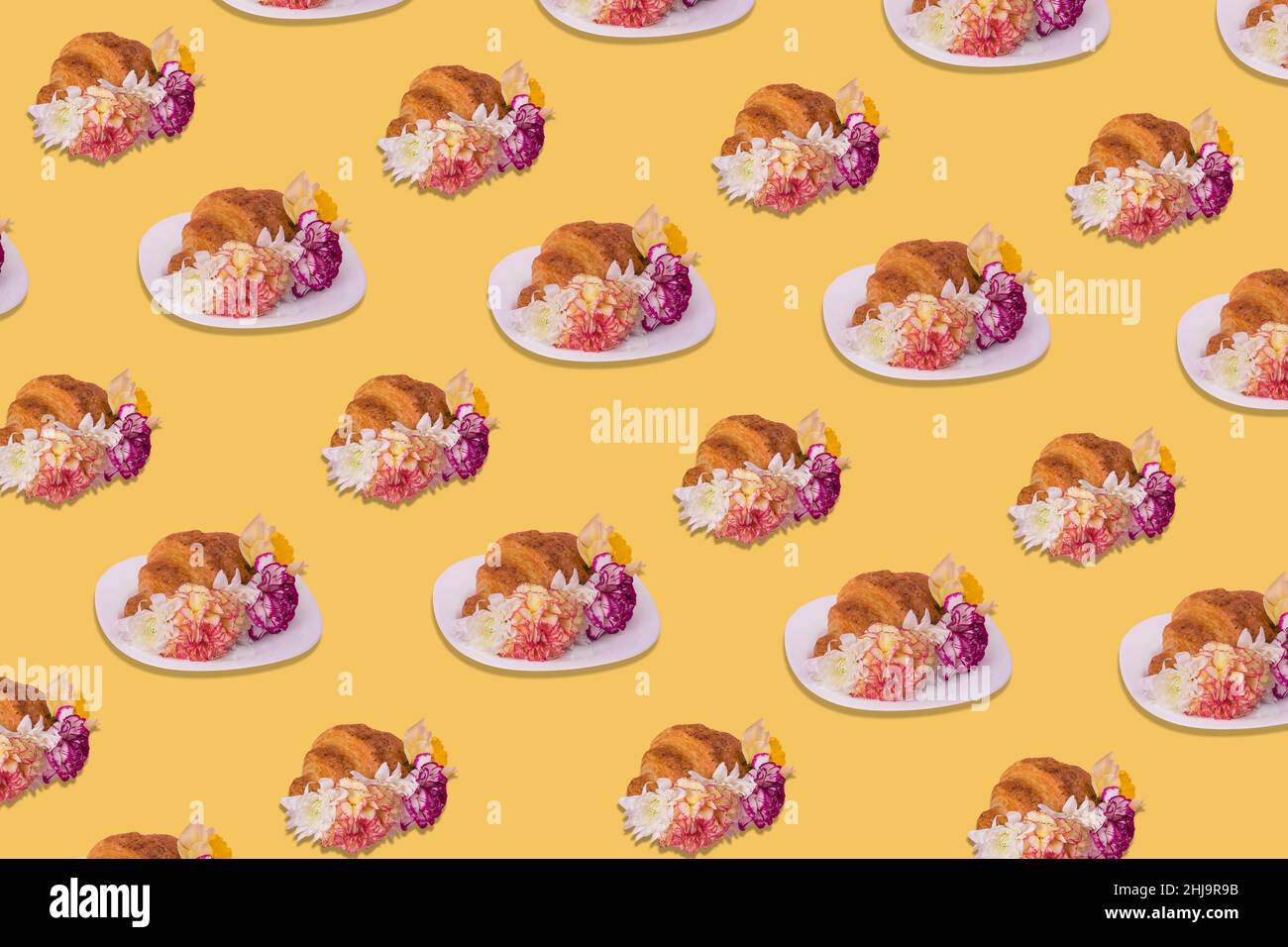 Creative pattern made of freshly baked croissant with flowers on pastel yellow background. Minimal spring or summer concept. Modern fun concept of sty Stock Photo