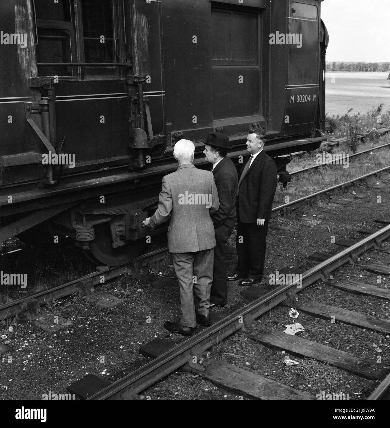 1963 Great Train Robbery was the robbery of £2.6 million from a Royal Mail train heading from Glasgow to London on the West Coast Main Line in the early hours of 8th August 1963, at Bridego Railway Bridge, Ledburn, near Mentmore in Buckinghamshire, England. Our Picture Shows ... Detective Superintendent Malcolm Fewtrell, Head of Buckinghamshire CID and Det. Supt. Gerald McArthur of Scotland Yard (wearing hat) examine  the mail carriage in the sidings at Cheddington Train Station, Friday 9th August 1963. Stock Photo