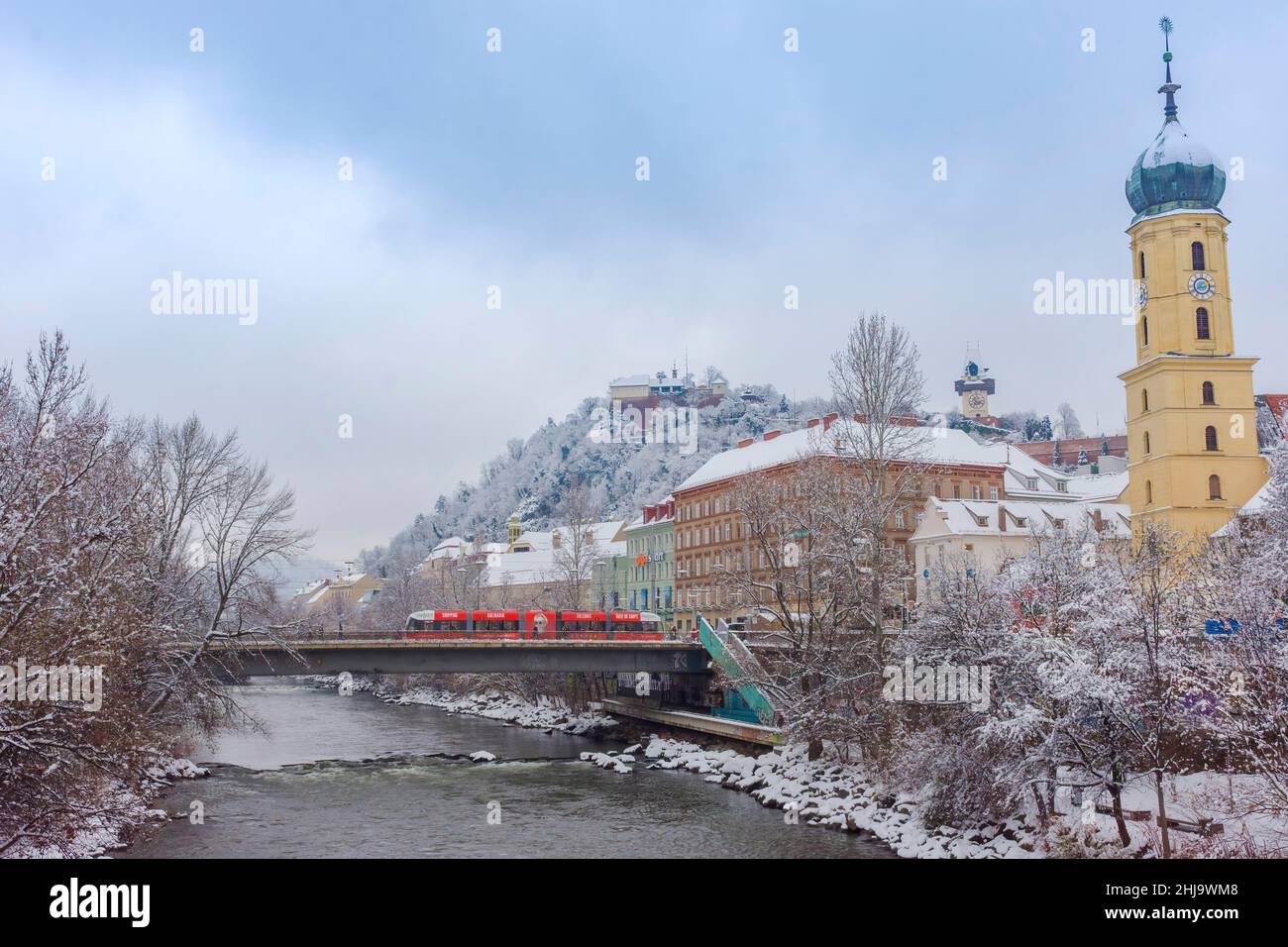 Graz, Austria-December 09, 2021: Mur river, the Franciscan Church tower and the famous clock tower in the background, in the city center of Graz, Stei Stock Photo