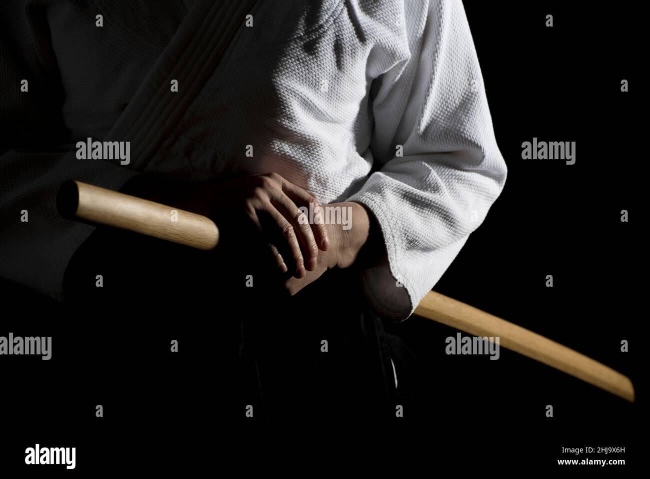 Aikido hakama, japanese martial arts uniform on black background. Shallow depth of field. SDF. A girl in black hakama standing in fighting pose with w Stock Photo