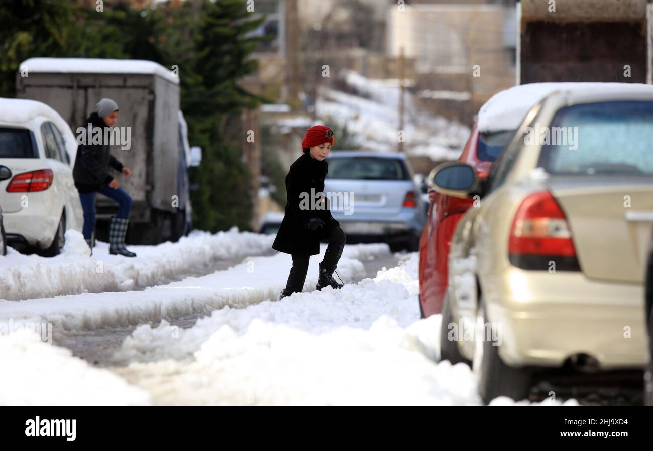 Amman, Jordan. 27th Jan, 2022. People cross a snowcovered road in